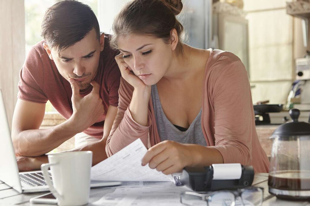 Young couple reviewing finances at kitchen table